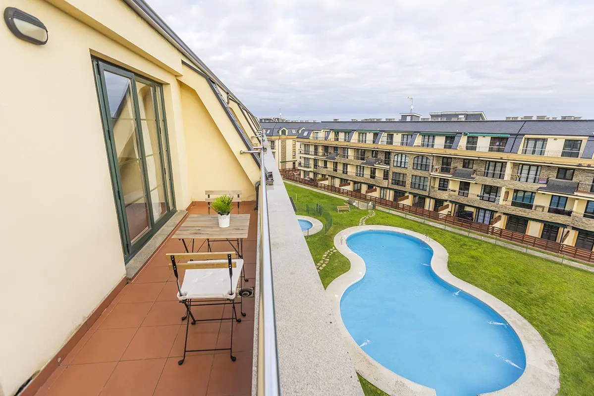 Terraza de un ático en Barreiros con mesa, sillas y vista a la piscina y el jardín comunitario