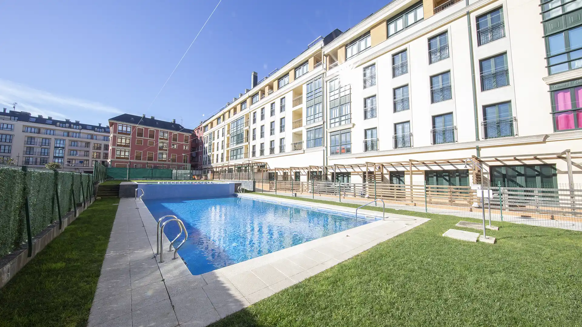 Piscina exterior con césped y pérgola de un edificio de apartamentos en Foz, Lugo
