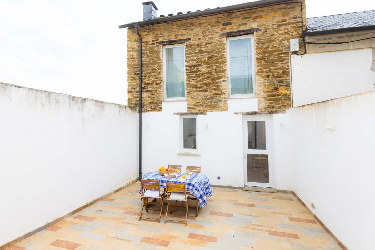 Terraza interior de piedra con mesa y sillas de madera en la Casa de Ribeira, alojamiento de Apartagal