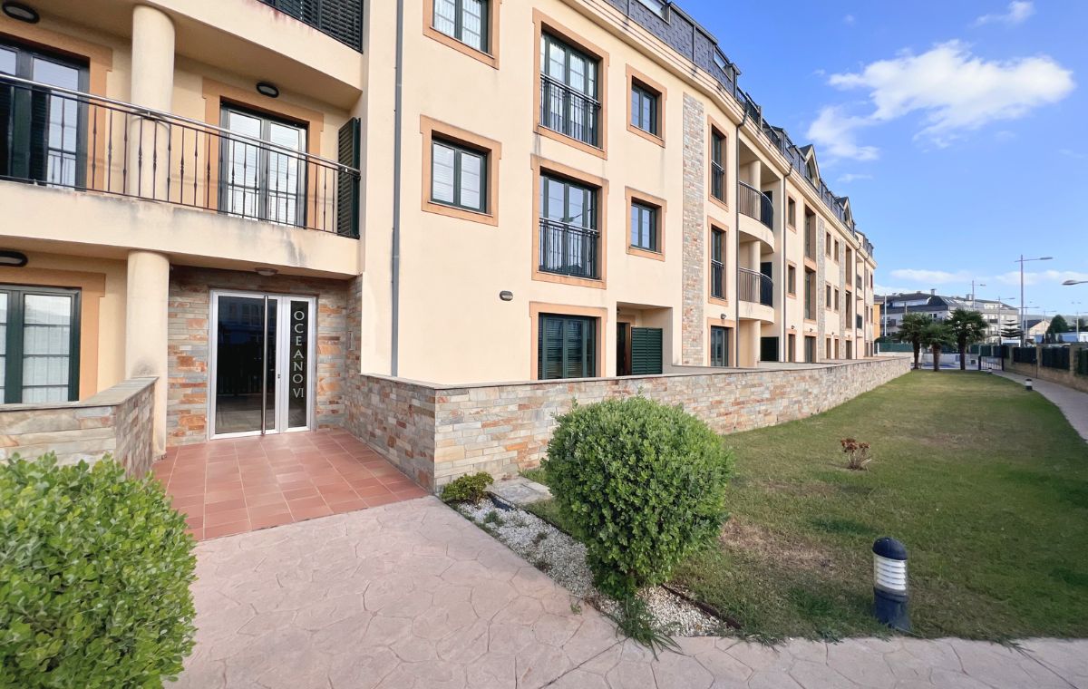 Fachada del edificio Océano VI con balcones, jardín y entrada acristalada, apartamentos de Apartagal